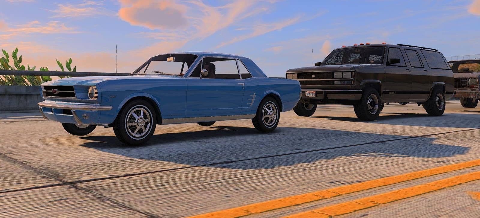 Une berline bleue de 1966 et un break noir garés sur la jetée au coucher du soleil